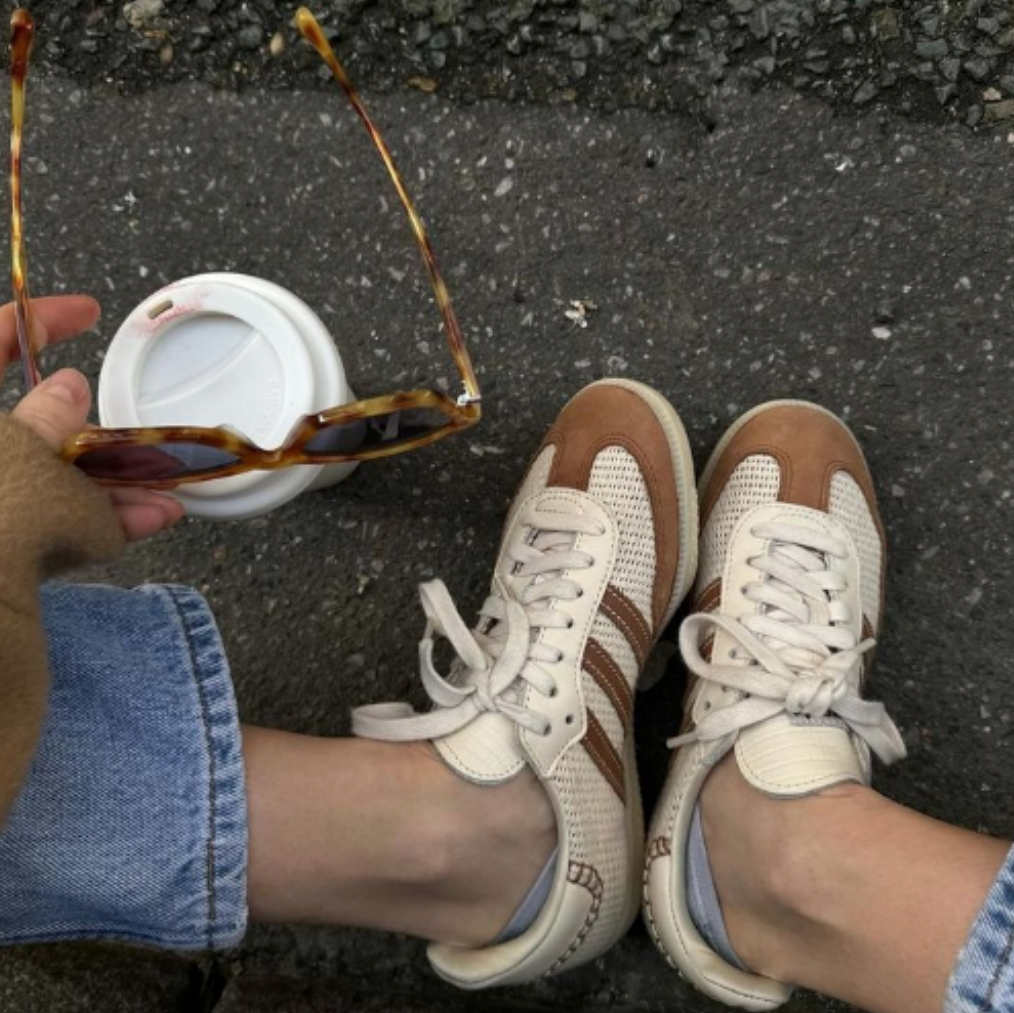 Weiß Braune Adidas Samba Sneaker, Sonnerbrille in der Hand, Kaffeebecher steht neben den Schuhen