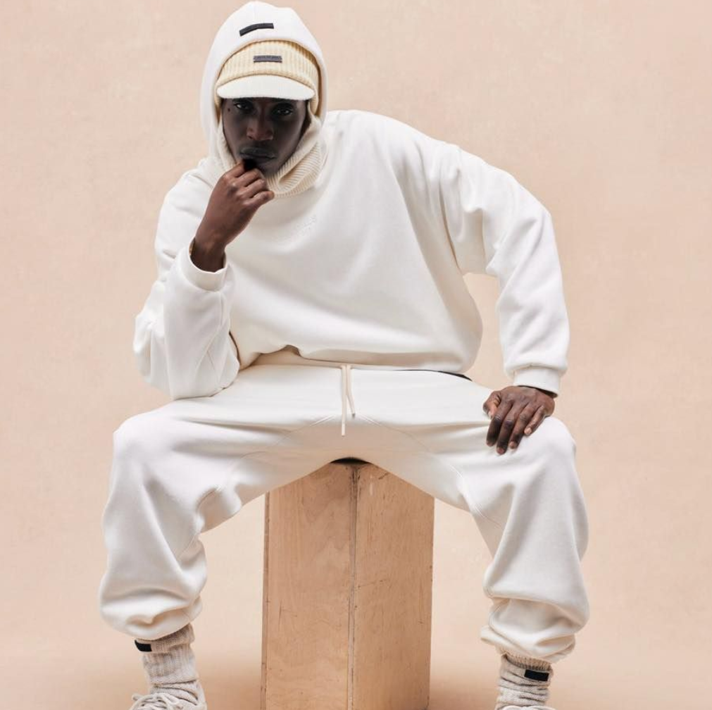 Mann mit weißer Jogginghose und Weißem Hoodie von fear Of God Essentials 