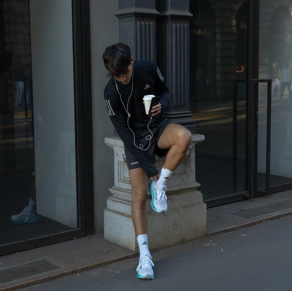 Jogger rückt seinen Running Sneaker zurecht stehend vor einem Ladengeschäft