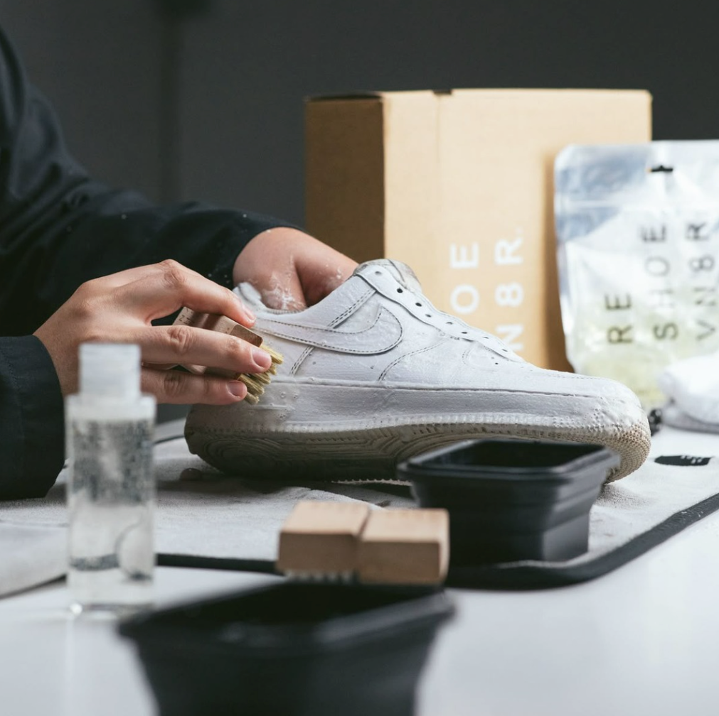 Mann reinigt weiße Air Force 1 mit einem schwamm