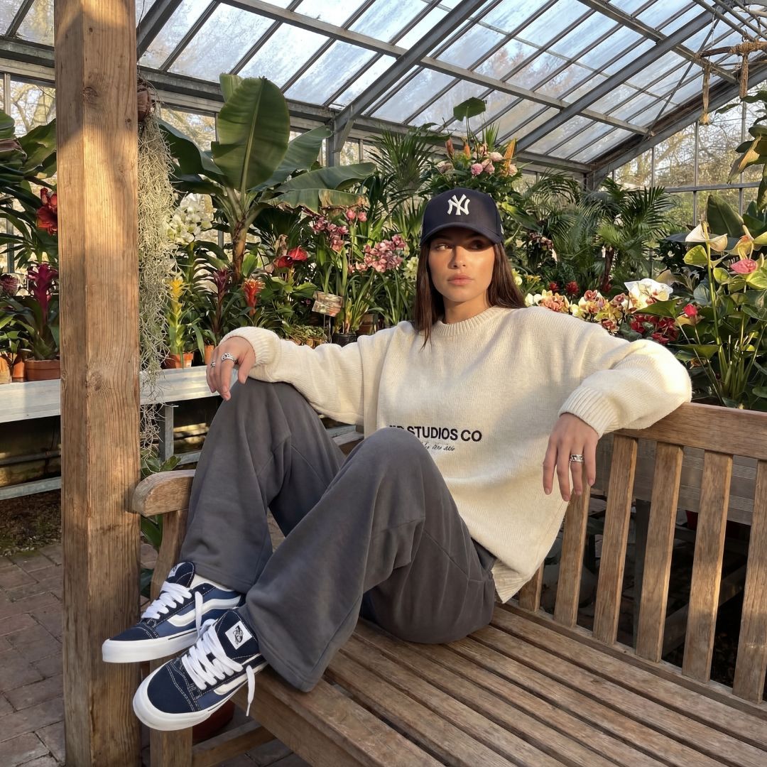 Frau sitzend auf einer Treppe mit weißen New Balance Sneaker und schwarzer Hose mit Beige Mantel