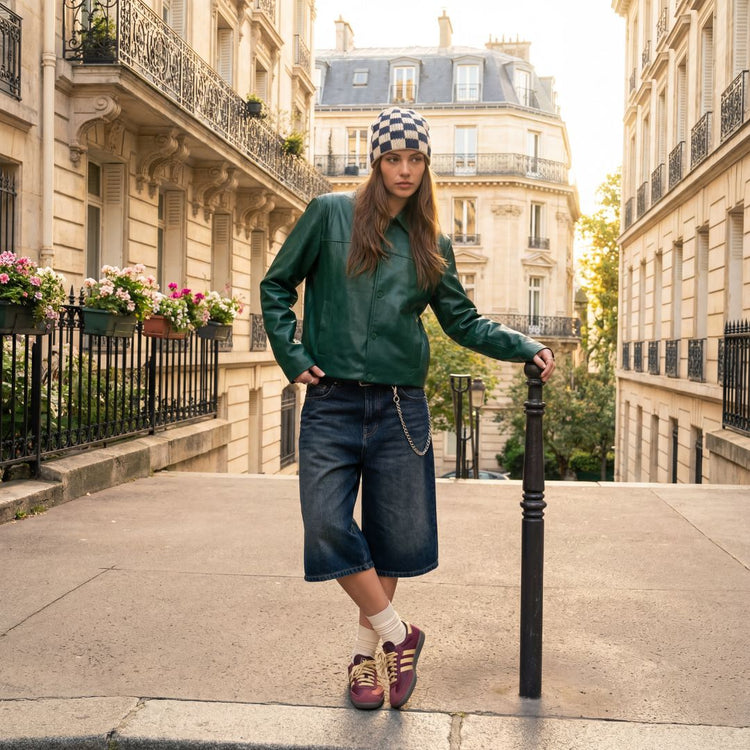 Frau steht lehnend auf der Straße und trägt ein paar Adidas SL. 