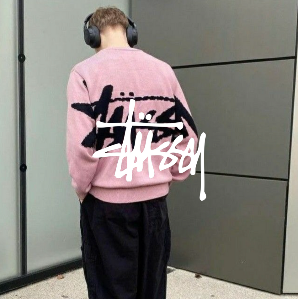 Stussy Logo mit einem mann in rosa Sweatshirt und schwarzer Hose vor einem Gebäude