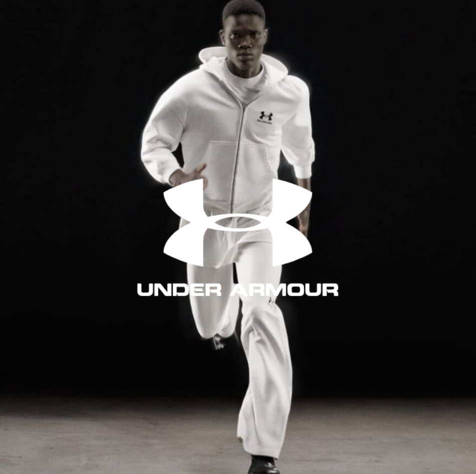 Under Armour Logo, Mann in weißem Outfit und schwarzen Sneakern Online kaufen