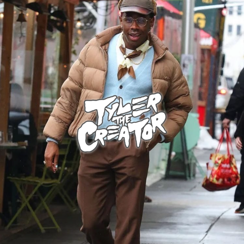 Tyler The Creator läuft in blauem sweater und brauner Jacke sowie Hose eine Straße entlang