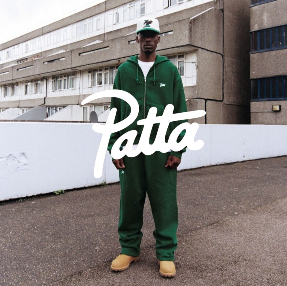 Patta Logo, Mann in grünem Tracksuit mit Timberlands vor urbanem Hintergund