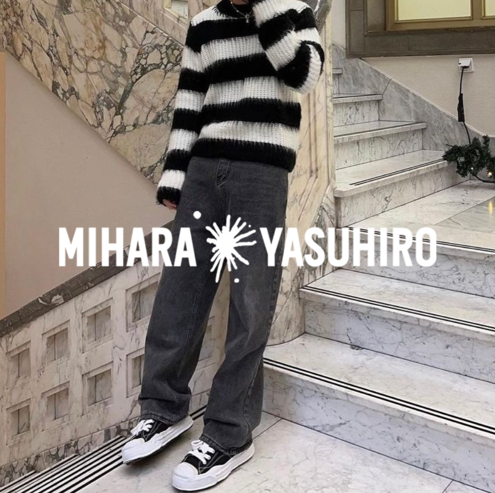 Mihara Yasuhiro Logo, mit Mann in Hank Sneakern, jeans und gestreiftem Sweater stehend in einem treppenaufgang