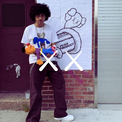 KAWS Logo, Mann mit schwarzer Jeans, weißem t Shirt und Sneakern vor urbanem Hintergund