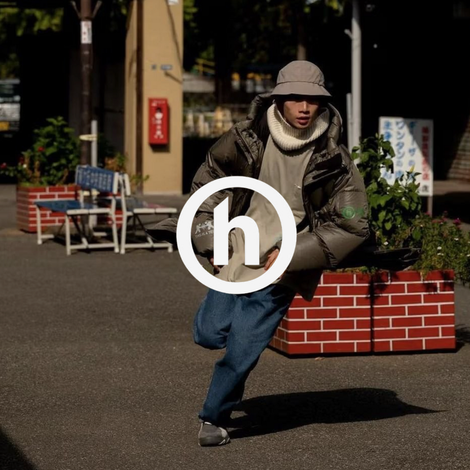 Hidden NY Logo mit einem Mann rennend vor einem Cafe in Puffer Jacket, hoodie und Jeans