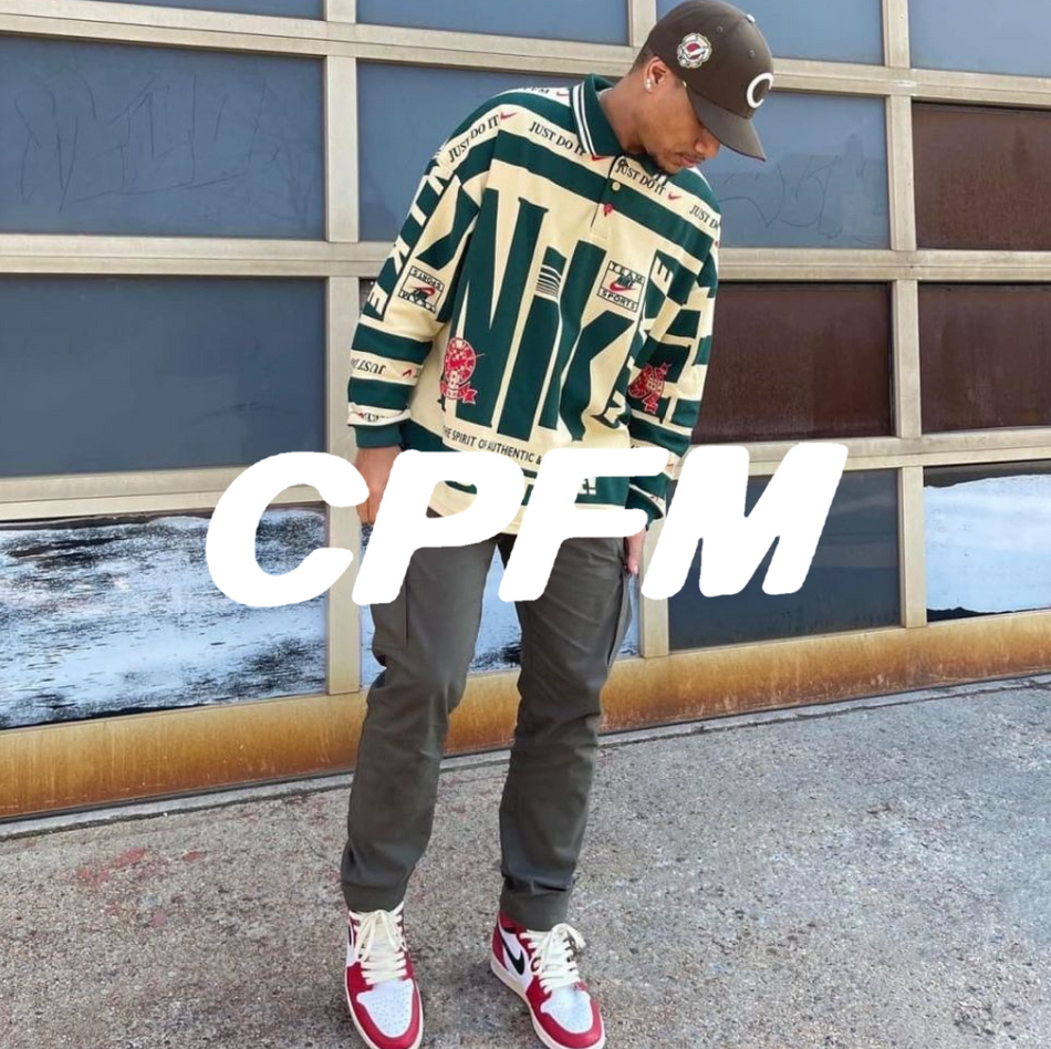 CPFM LOGO Mann im Hintergund mit gelb grüner Jersey vor einer Wand. Rot weiße Air Jordan 1 und eine graue Cargo Pants