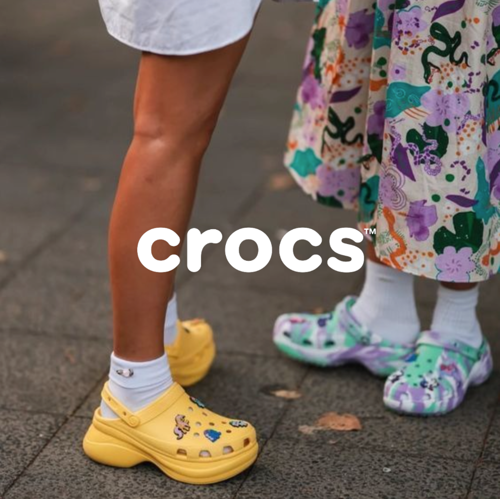 Gelbe Crocs Clogs und Lila Grüne Clogs stehend auf dunklen Platten