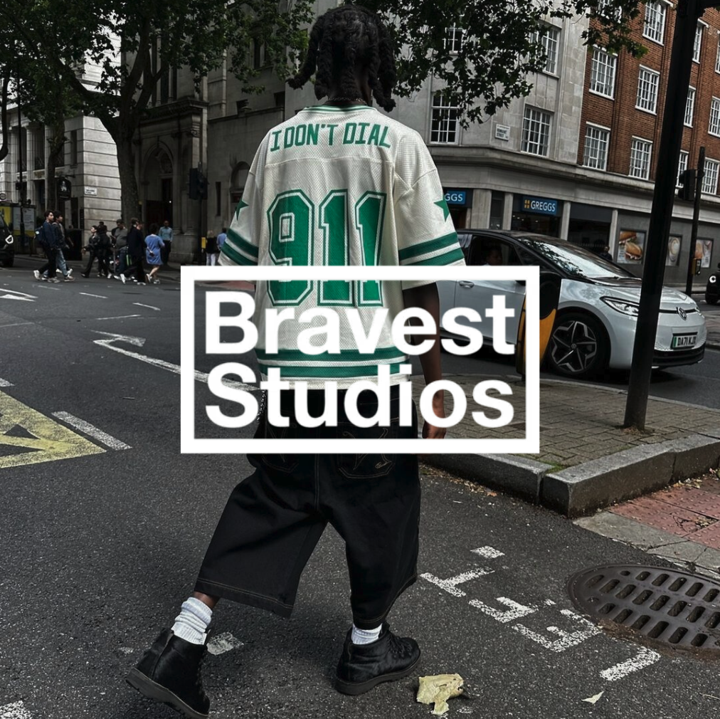 Bravest Studios Logo mit einem Mann in weiß grüner Jersey mit schwarzer hose und jeans vor urbanem Hintergund
