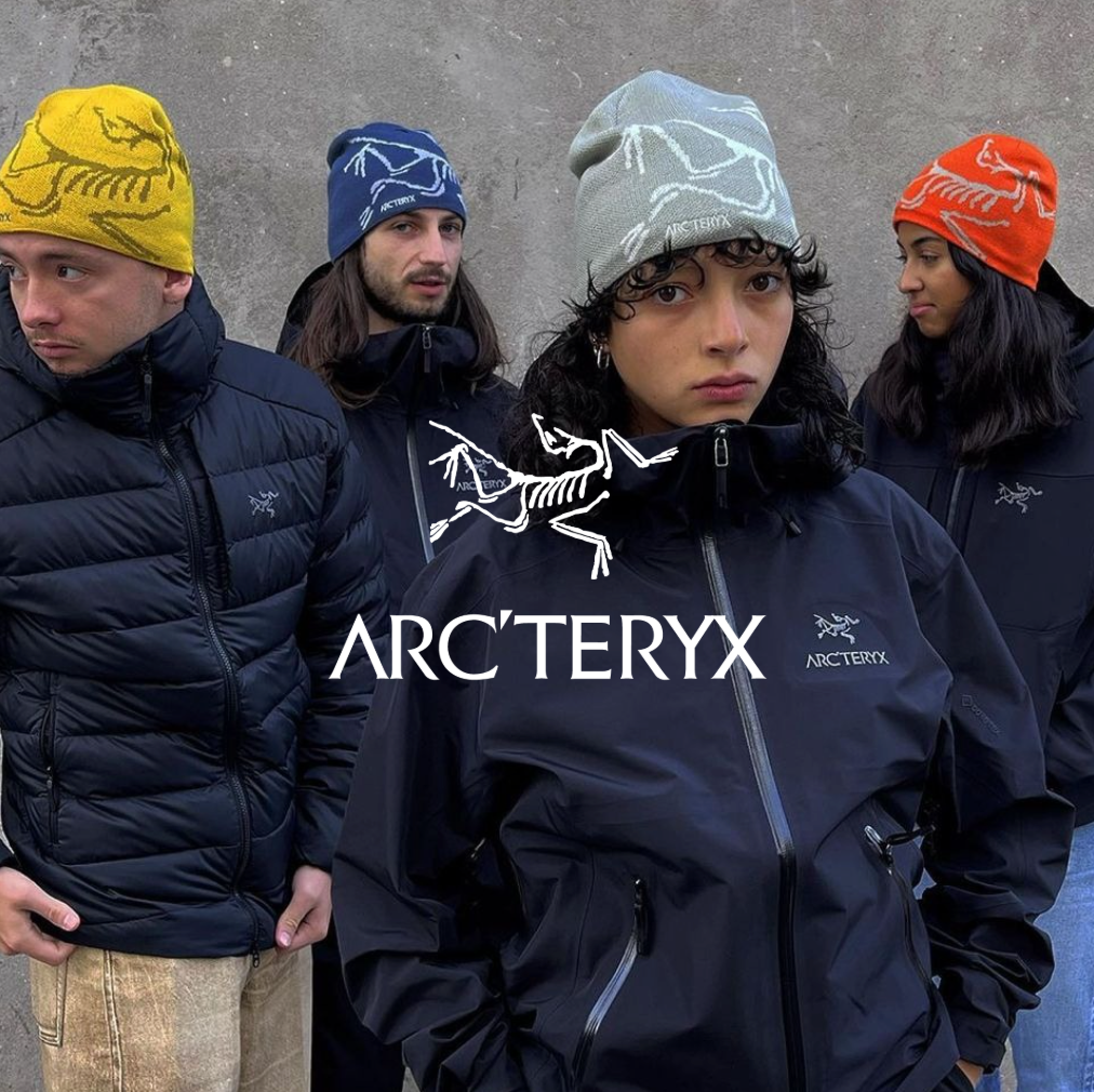 Arc´teryx Logo mit 4 Models in schwarzen jacken und bunten Mützen vor grauer Wand