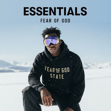 Essentials Fear Of God Logo mit einem Mann in Essentials Hoodie auf einem schneebedeckten Berg mit Gebirge im Hintergund
