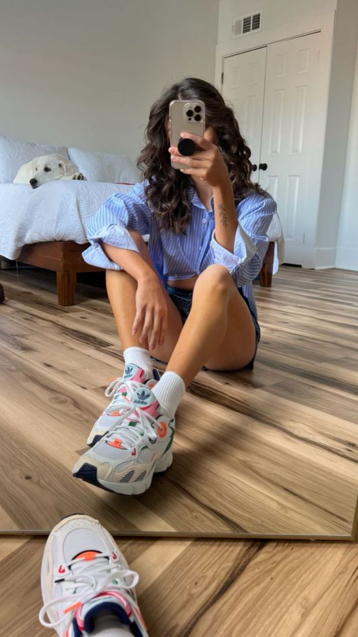 Frau in Schlafzimmer mit Adidas Sneakern und blau weißer Bluse 