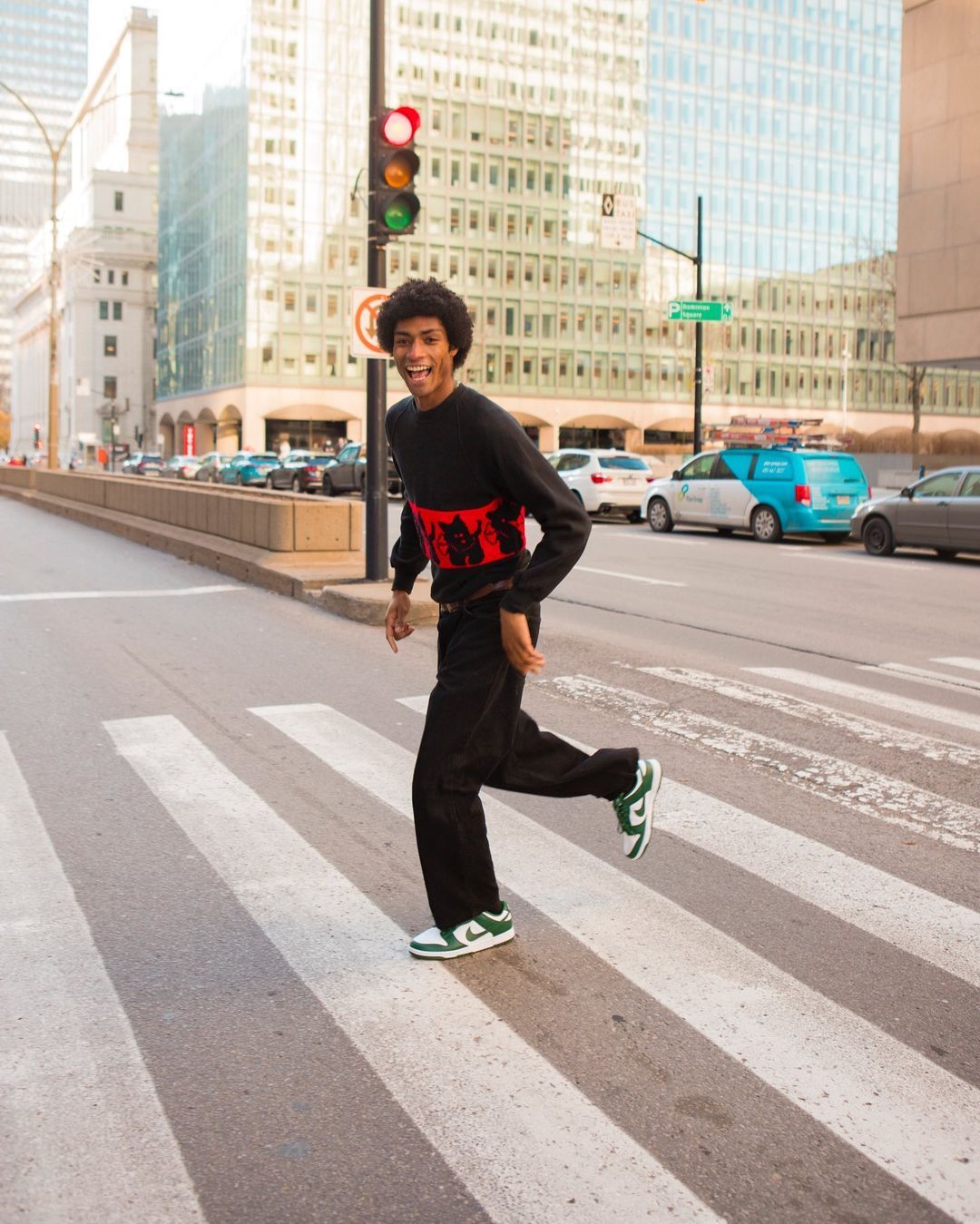 Junger Mann auf einem großen zebrastreifen mit Nike Dunk Low in Grün Weiß mit Schwarzem Outfit