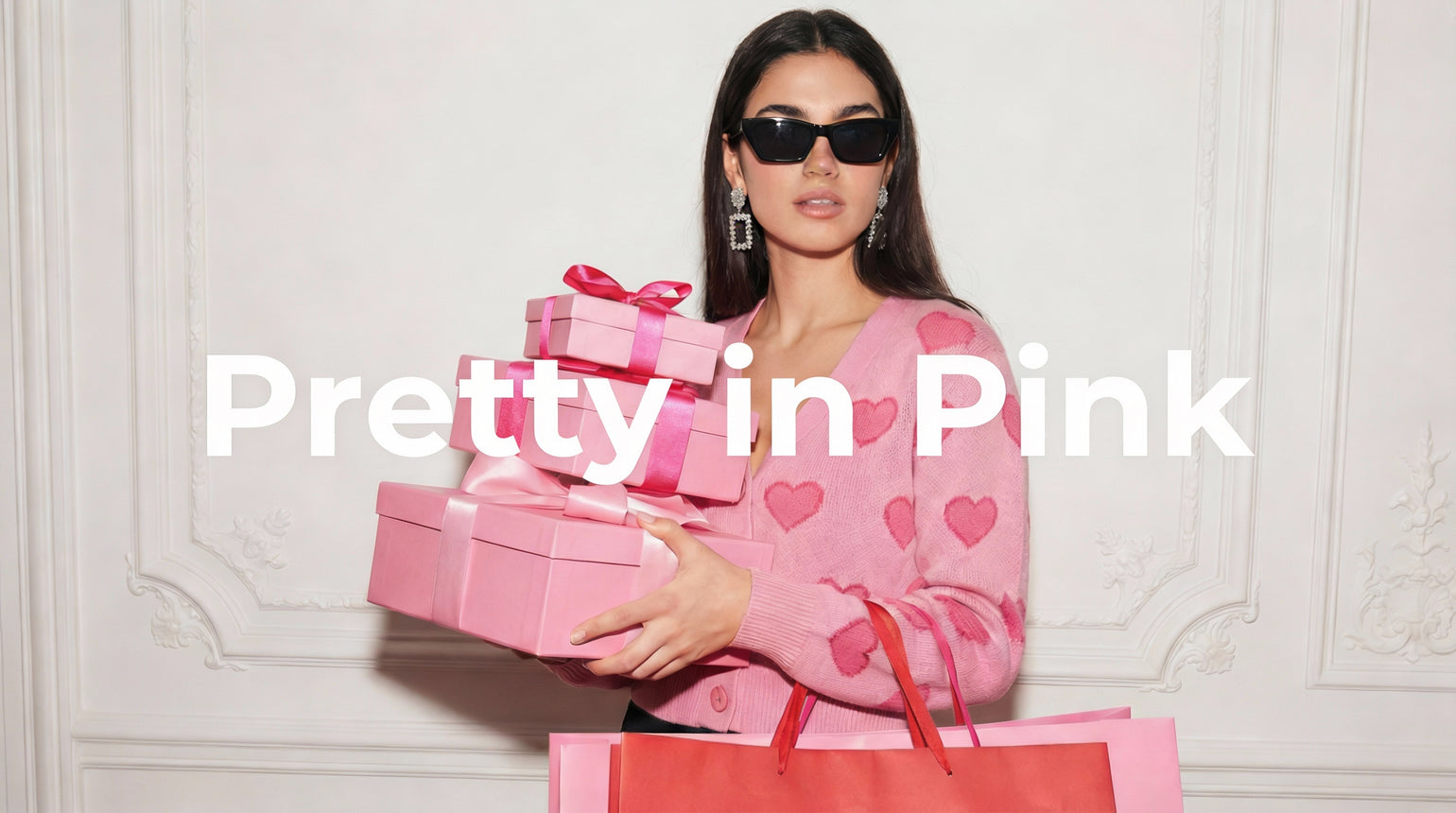 Pretty in Pink, Frau mit pinker Kleidung und pinken Geschenken steht vor einer weißen Wand