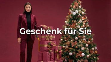 Geschenke für Sie eine Frau in rotem Sakko lehnend auf rot goldenen Geschenken neben einem Weihnachtsbaum