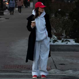 Frau in grauer Sweatpants und hoodie steht auf einer Straße